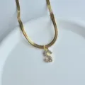 Close up of gold herringbone chain necklace featuring a sparkling zircon letter S pendant. - S
