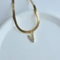 Close-up of a gold flat herringbone chain necklace featuring a sparkling zircon V letter pendant. - Letter V