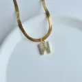 Detail shot of gold herringbone chain necklace with rhinestone letter W pendant chic. - Letter W