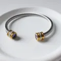 Detailansicht eines Edelstahl-Kabelarmbands mit goldenen Endkappen und lila Steinen. - Februar