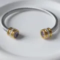 Nahaufnahme des Edelstahl-Kabelarmbands mit lila Stein und Kristallen auf weißem Teller. - Juni