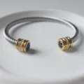 Detailaufnahme eines Edelstahldraht-Armreifs mit blauem Stein und funkelnden Strass-Goldkappen. - Dezember