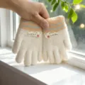 Primo piano di guanti invernali in maglia per bambini con fodera calda e grazioso cerotto. - Taglia unica / Cachi portafortuna