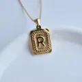 Close-up detail of a gold stainless steel square letter R pendant necklace on white dish. - Letter R Square Pendant / Gold