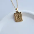 Gold stainless steel square pendant necklace detail shot featuring embossed letter X design. - Letter X Square Pendant / Gold