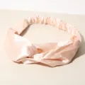Close-up detail of a soft peach satin twisted headband featuring a silky smooth texture. - Apricot
