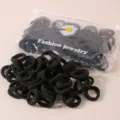 Nahaufnahme von schwarzen Haargummis im Set mit Gänseblümchen-Verpackungsbeutel. - Hochelastische Haargummis in Beutel / 50 Stück Beutel / Schwarz