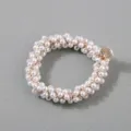 Close-up detail of a handmade white pearl hair scrunchie with a gold metal charm - White