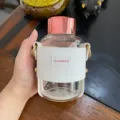 Detail einer klaren Glas-Wasserflasche mit weißer Lederhülle und Roségold-Deckel - 520ml / Weiß