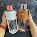 Detailansicht von zwei hitzebeständigen Glastrinkflaschen mit Lederhüllen und Trageriemen - 450ml / Braun