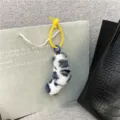 Detailed view of a leopard plush charm accessory hanging on a stylish gift bag. - White Grey Leopard