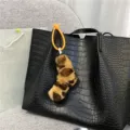 Close-up of a trendy leopard print plush twisted charm attached to a black crocodile bag - Brown Leopard Print