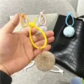 Close-up detail of a cute fluffy brown plush ball charm with a yellow silicone strap - Single OPP Bag Packaging / Khaki