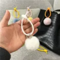 Close-up of a white plush pompom bag charm with a flexible silicone ring loop - Single OPP Bag Packaging / White
