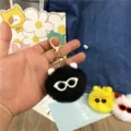 Detailed macro view of a cute black fuzzy soot sprite keychain with sunglasses decoration - Black
