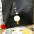 Detailed view of a cute plush ice cream cone keychain with pearl charm on a black leather bag - Single Piece / White