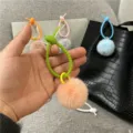 Close-up of a colorful silicone strap with a soft peach plush pom-pom bag pendant. - Single OPP Bag Packaging / Pink