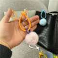 Close-up of a pink plush pom-pom keychain with an orange spiral ring held in hand - Single OPP Bag Packaging / Pink