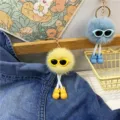 Detail shot of cute pom-pom character keychains with sunglasses and tiny shoes. - Yellow