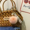 Macro view of creative floral ribbon and pink plush pom-pom keychain with white pearl - Single Piece / Pink