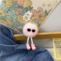 Detail of a pink fluffy monster keychain featuring sunglasses and tiny pink shoes - Pink