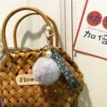 Detailed view of a cute floral strap keychain with a grey plush pompom and pearl - Single Piece / Gray