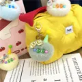 Detailed view of a cute fuzzy plush ball keychain with a mini cone hat on a yellow bag - Single OPP Bag Packaging / Green