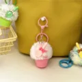 Close-up of a cute pink plush ice cream keychain charm hanging on a yellow textured bag. - Pink