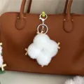 Close-up of white plush tofu-shaped bag charm with wooden sticks on brown leather bag - White