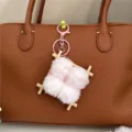 Creative fermented bean curd plush keychain charm hanging on a brown leather handbag - Pink