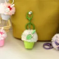 Close-up view of a cute green plush ice cream cupcake keychain hanging on a yellow bag - Green