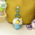 Detail view of a colorful plush ice cream cupcake keychain with a yellow spoon charm. - Teal
