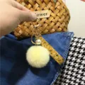 Close-up of a cute yellow fur pom-pom keychain featuring a floral ribbon and pearl charm - Single Piece / Goose Yellow