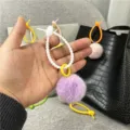 Detailed macro view of a purple plush pom pom bag charm with a white silicone ring - Single OPP Bag Packaging / Purple