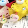 Close-up of a pink plush pom-pom keychain with an ice cream cone hat on a yellow bag. - Single OPP Bag Packaging / Pink