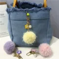 Close-up of fluffy pom-pom keychain with pearl and flower charms on denim bag - 1 Piece / Light Yellow