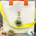 Close-up of cute monster plush ball keychains with glasses and pearl charms on bag - Single OPP Bag Packaging / Dark Green