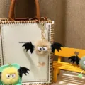 Close-up detail of cute furry bat monster plush keychain hanging on a stylish white bag - Single OPP Bag Packaging / Khaki