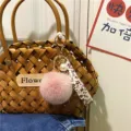 Detailed view of pink fur pom-pom keychain with floral strap and elegant white pearl. - Single Piece / Dusky Pink