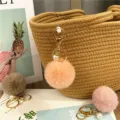 Close-up of cute plush pom pom keychain with pearl accent and gold-tone clasp - Orange Pink