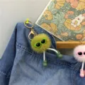 Close-up of cute fuzzy ball keychain with sunglasses and little boots on denim. - Avocado Green