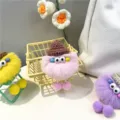 Detailed close-up of fuzzy monster keychains in pink, yellow, and purple colors. - Pink