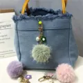 Detailed view of fresh flower pompom keychain with pearl and fur ball on a denim bag charm - 1 Piece / Green