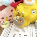 Detailed view of a cute grey plush ice cream keychain charm hanging on a yellow bag. - Single OPP Bag Packaging / Khaki