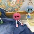 Close-up detail of creative plush ball keychains featuring cute glasses and tiny bow shoes - Rose Red
