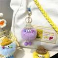 Close-up of colorful furry monster keychains with mini knit hats and cute bead details - Purple