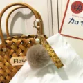 Close-up of a floral strap keychain with a grey pom-pom and pearl charm - Single Piece / Khaki