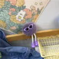 Close-up of cute purple fuzzy soot sprite doll keychain with sunglasses and shoes - Purple