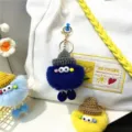 Cute fuzzy monster doll keychains in various colors attached to a white canvas bag - Sapphire Blue
