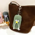 Ugly-cute plush monster keychain with beard hung on a brown suede bag as a stylish charm - Green